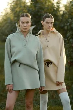 Two models in stylish tracksuits pose in apple orchard at sunset . The mode.. Fotos de archivo