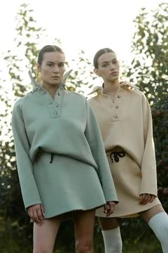 Two models in stylish tracksuits pose in apple orchard at sunset . The mode.. Stock Photos