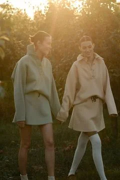 Two models in stylish tracksuits pose in apple orchard at sunset . The mode.. Stock-Fotos