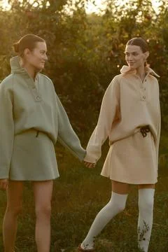 Two models in stylish tracksuits pose in apple orchard at sunset . The model  Stock Photos