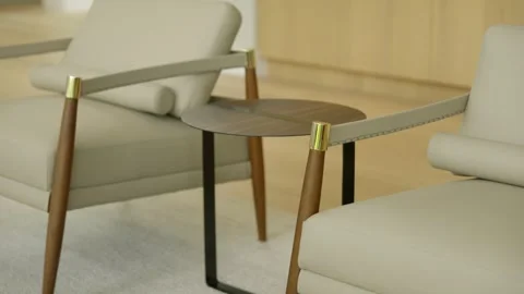 Two modern armchairs with light beige cushions and wooden legs, positioned Stock Footage 297751005