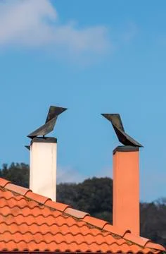 Two modern brick chimneys with wind cone on the roofs Stock Photos