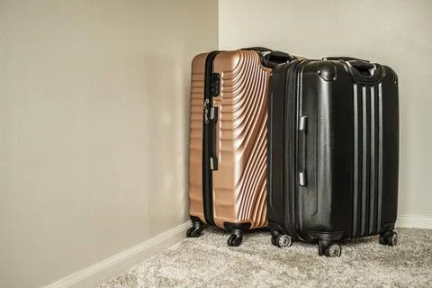 Two modern hardshell suitcases standing in the room corner on the carpet Stock Photos