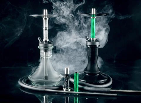 Two modern hookahs with smoke on a black mirror background. Stock Photos