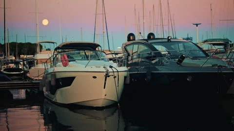 Two modern motorboats moored side by side in a marina just after sunset, under a Vídeos de archivo 322689474