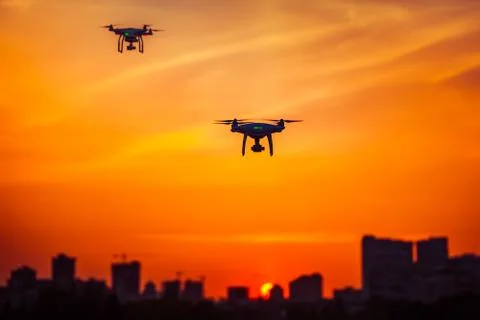 Two modern Remote Control Air Drones Fly with action cameras in dramatic orange Fotos Stock