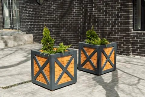 Two modern square planters with geometric gray frames and warm wooden panels 스톡 사진