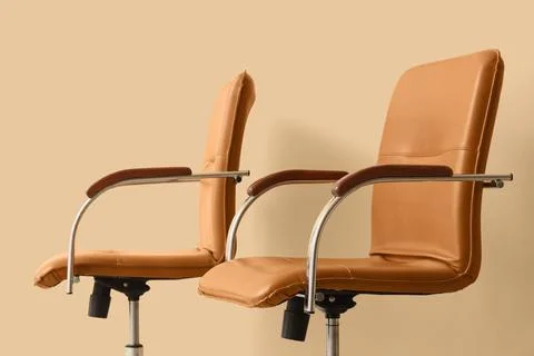 Two modern tan leather office chairs with chrome and wood accents, contempora Stock Photos