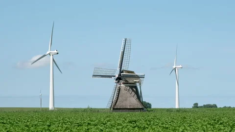 Two modern white windturbines behind an old traditional dutch windmill Stock Footage 201953392