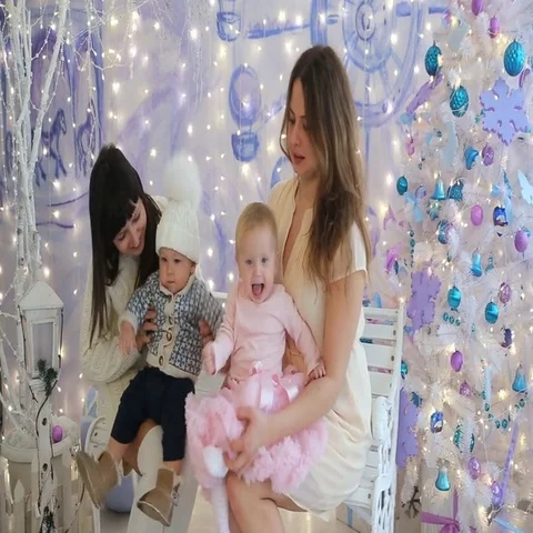 Two mom with little boy and girl sitting on a bench in Christmas studio Stock Footage 69458483