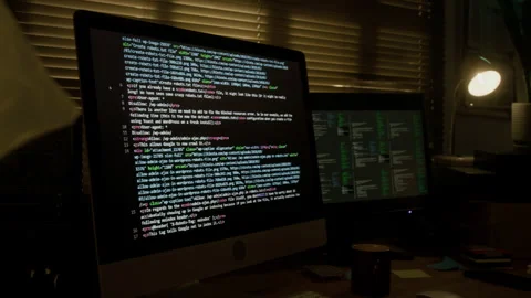 Two Monitors Displaying Code in Dimly Lit Room of Programmer Video stock 302949612