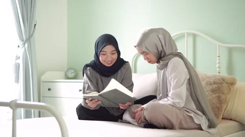 Two moslem female sibling learning read smile happy together bedroom home Stock Footage 299182741