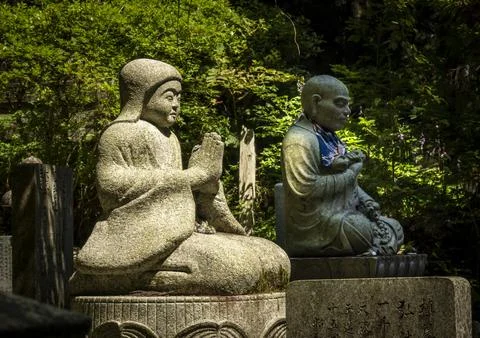 Two moss-covered stone statues of praying monks in Koyasan cemetery, Wakaya.. Stock Photos