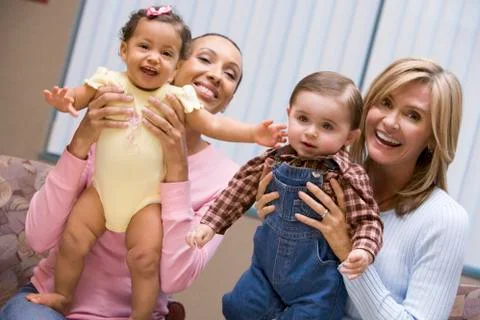 Two mothers holding two IVF children smiling Stock Photos