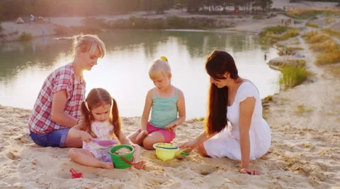 Two mothers playing sand with two daughters 3 and 5 years Stockbeeldmateriaal 66060388