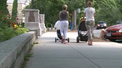 Two mothers pushing strollers down sidewalk Video stock 8981391