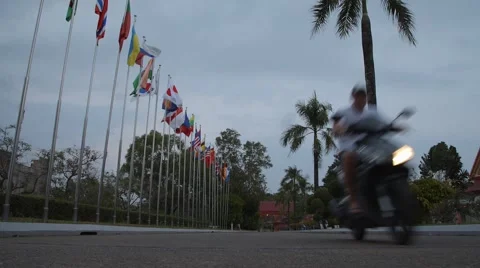 Two motorbikes passing by on the background of international flags Stock Footage 49409079