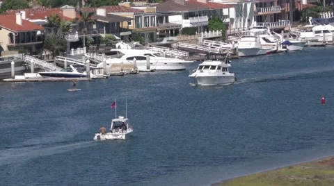 Two motorboats crossing paths in tight channel with paddle boarder oceanfront Video stock 67555585