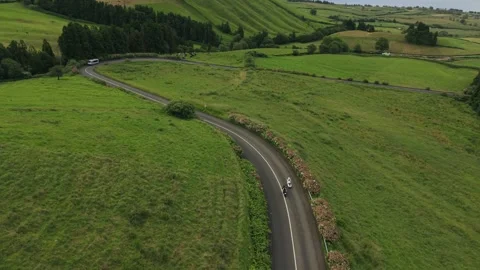Two Motorcycles Riding Winding Road Through Azores Pastures Stock Footage 347125602