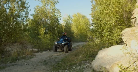 Two motorcyclists on ATVs ride on a mountain road in the forest. Stock Footage 126559138