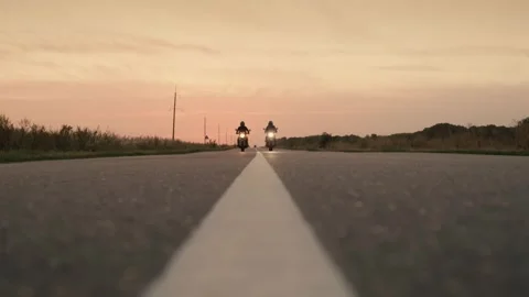 Two motorcyclists riding on empty highway towards sunset with headlights on. Stock-Footage 335063218