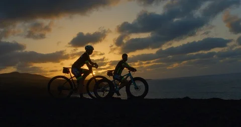 Two mountain bikers arrive at the Ocean a sunset. Vídeo Stock 85528531