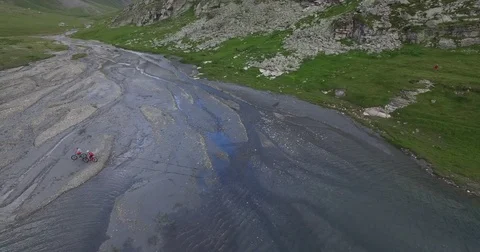 Two mountain bikers crossing a river and river bed. Vídeo Stock 78031553