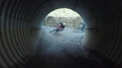 Two mountain bikers cycle through large underground tube, drone aerial 4K Stock Footage 101108291