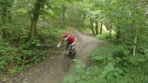 Two mountain bikers going over small jump through forest, drone aerial 4K Stock Footage 101106801