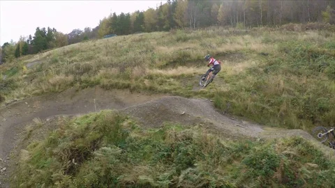 Two mountain bikers jumping a huge gap into a large berm, drone aerial 4K Stock Footage 101109690