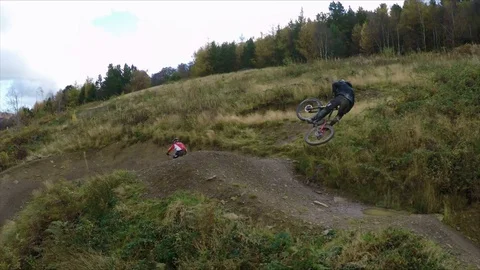 Two mountain bikers jumping a huge gap and performing tricks, drone aerial 4K Stock Footage 101109758