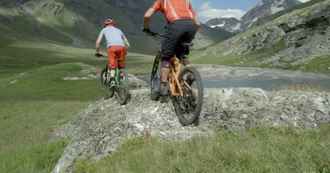 Two mountain bikers riding a rock face in a mountain range Vídeo Stock 78030573