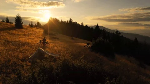 Two mountain bikes and a tent on a mountain meadow at sunrise in autumn 스톡 동영상 119277310