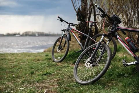 Two mountain bikes stand on the river bank. Atmospheric dynamic light. Picnic Stock Photos
