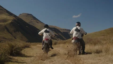 Two mountain motorcyclists start aggressively on a rocky mountain road. Mountain Stock Footage 239340198