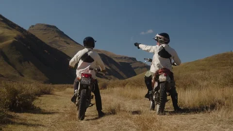 Two mountain motorcyclists start aggressively on a rocky mountain road. Mountain Stock Footage 247439796