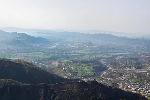 Two mountain ranges separating a city and a river bridge shot from a hill top. Stock Photos