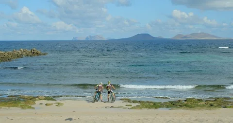 Two mountainbikers ride up to the oceans edge and look at the view. Vídeo Stock 86133526