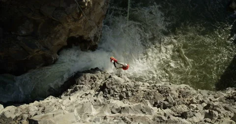 Two mountaineers rappelling over waterfall in a canyon Vídeo Stock 64337532