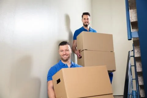 Two Movers Carrying Cardboard Boxes On Staircase Foto stock
