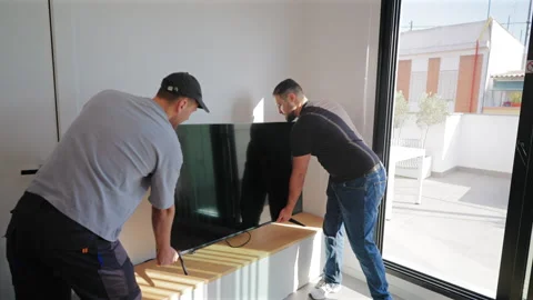 Two Movers Carrying Television at Home and Positioning Large Flat Screen TV. Stock Footage 342915639
