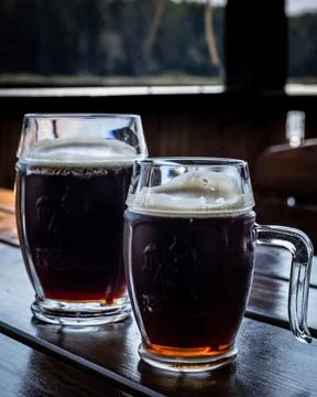 Two mugs of dark beer. Stock Photos