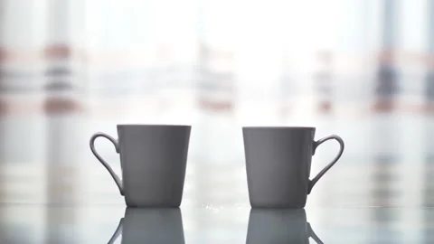 Two mugs with a hot drink stand on a glass table, there is steam, copy space Stock Footage 132447876