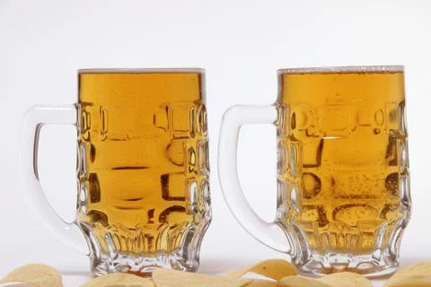 Two mugs of light beer and salty chips Stock Photos