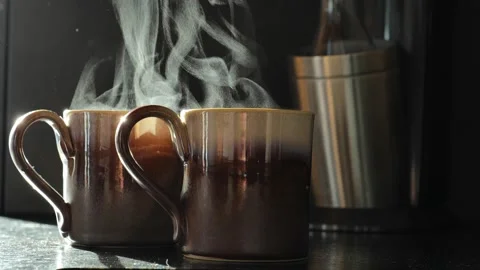 Two mugs of tea steaming on a black table Stock Footage 240854742