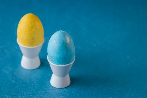 Two multi-colored decorative eggs on blue background. Easter concept. Stock Photos
