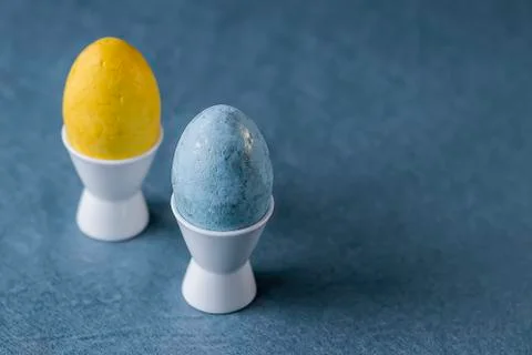 Two multi-colored decorative eggs on blue background. Easter concept. Stock Photos