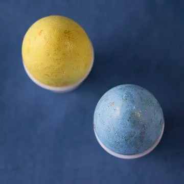 Two multi-colored decorative eggs on blue background. Easter concept. Stock Photos