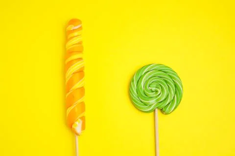 Two multi-colored lollipops on a yellow background. Foto stock