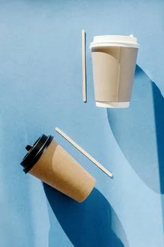 Two multi-colored paper cups for coffee and wooden sticks for mixing sugar li Stock Photos